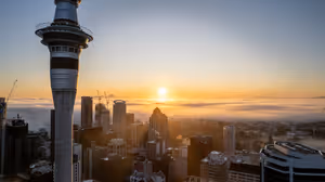 Gün doğumunda Auckland'da Sky Tower ve şehir merkezindeki yüksek binalar, arkalarında şehri örten alçak sis