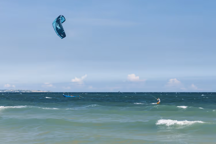 Okyanus dalgalarında uçurtmasıyla kite sörfçüsü