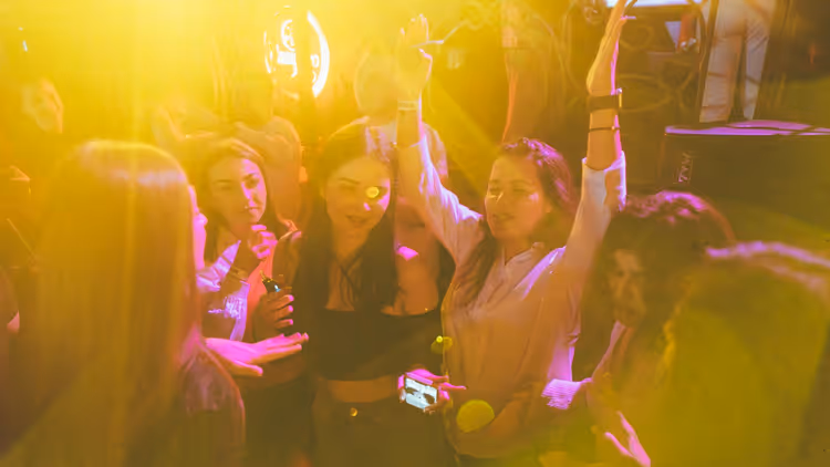 Amigos divirtiéndose en una discoteca bajo una luz amarilla
