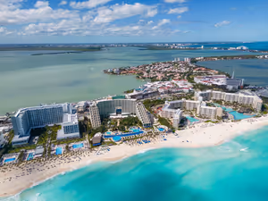 Luftaufnahme großer Resorthotels mit Pools auf einem weißen Sandstreifen zwischen türkisfarbenem Meer und Lagune in Mexiko