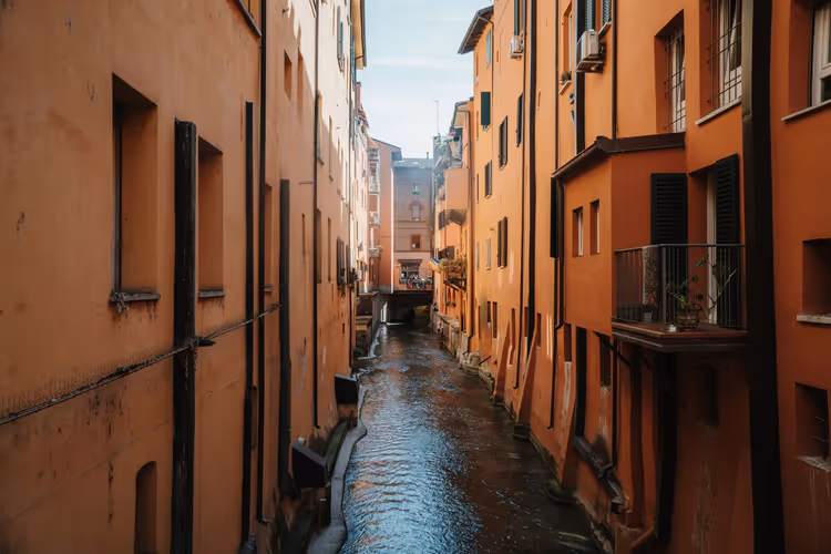 Smalt kanalsystem mellom oransje hus i Bologna