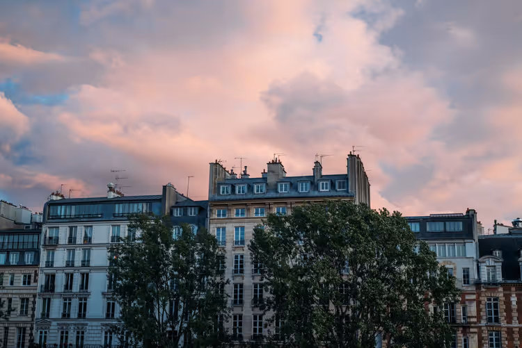 Pembe bulutlu gökyüzü altında mansart çatılı Paris cepheleri