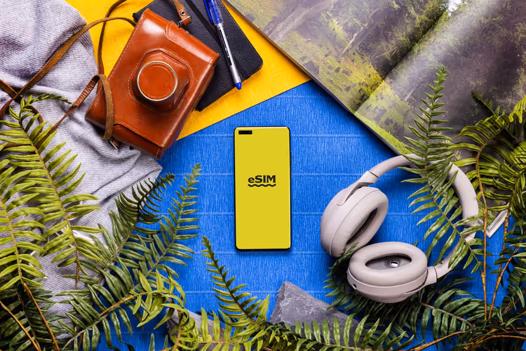 Smartphone mit eSIM-Logo, umgeben von Reiseutensilien