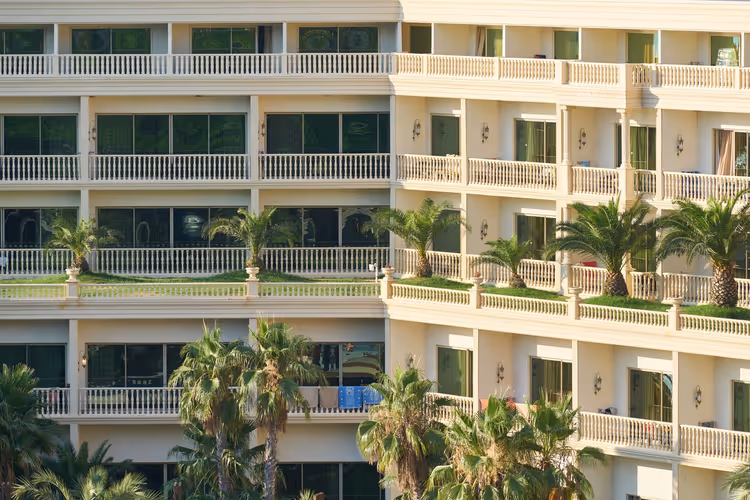 Balkonlar ve palmiye ağaçlarıyla apart otel cephesi