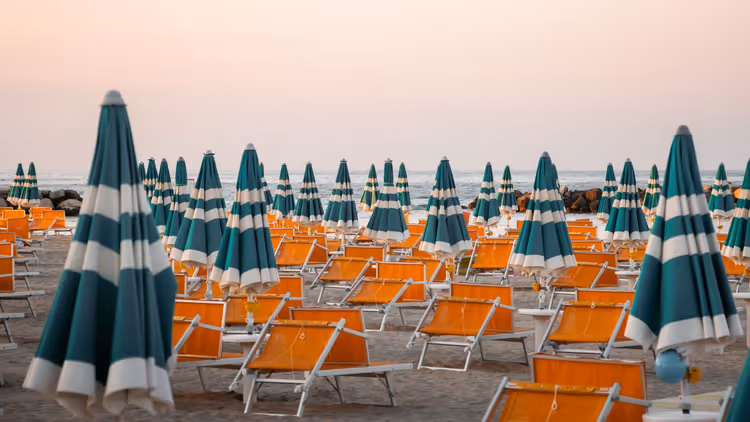 Zandstrand met gestreepte parasols en ligstoelen