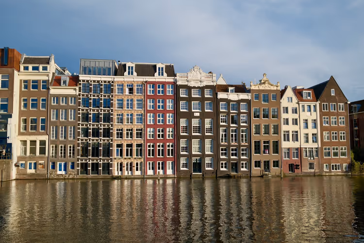 Reihe historischer Häuser entlang einer Gracht mit Spiegelung im Wasser