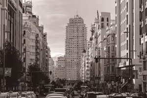 Sepia-Blick entlang einer belebten Madrider Allee mit prunkvollen Bauten des frühen 20. Jahrhunderts auf einen hohen gestuften Turm