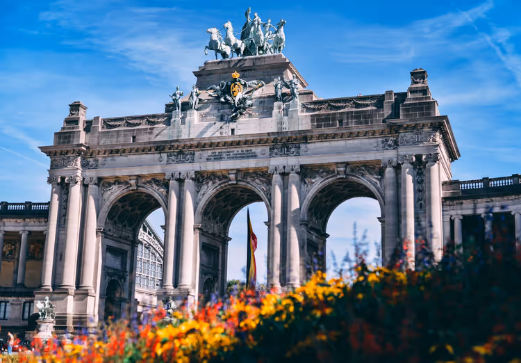 Triumphbogen im Jubelpark in Brüssel mit bronzener Quadriga, im Vordergrund leuchtend bunte Blumen