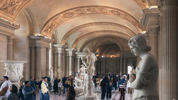 Ruime Louvre-zaal met antieke beelden en bezoekers