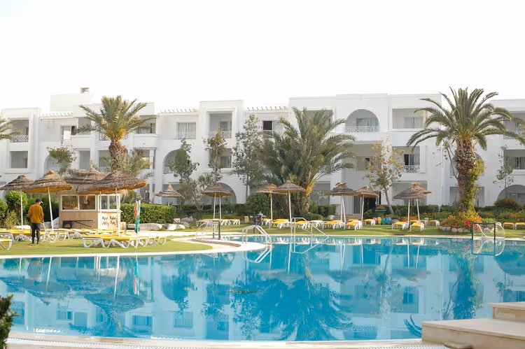 Basseng på resort-hotell med palmer og solsenger