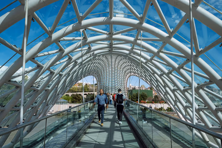 Folk som går inne i den glasskledde Fredsbroen i Tbilisi