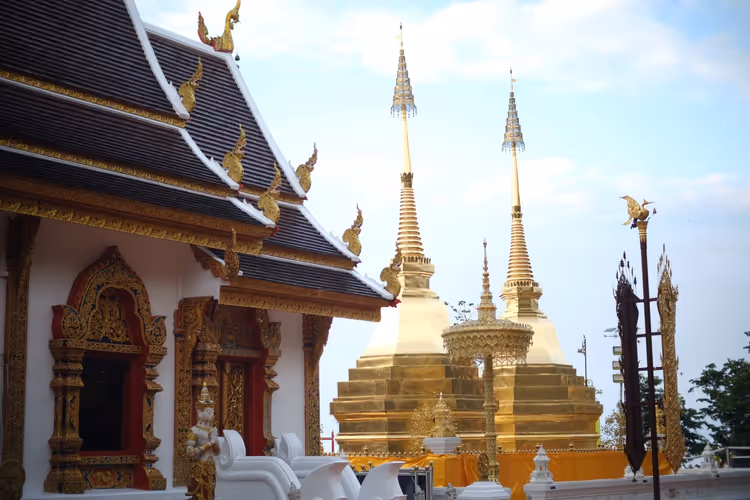 Goldene Turmspitzen eines thailändischen Tempels vor dem Himmel