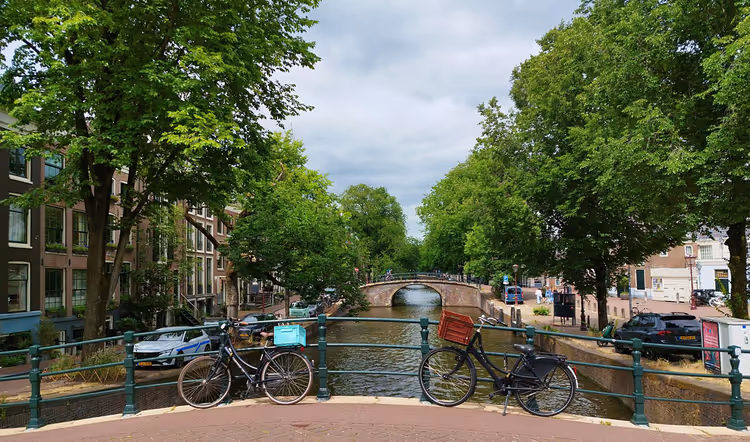 Amsterdam kanalı üzerindeki köprü korkuluğunun yanında bisikletler