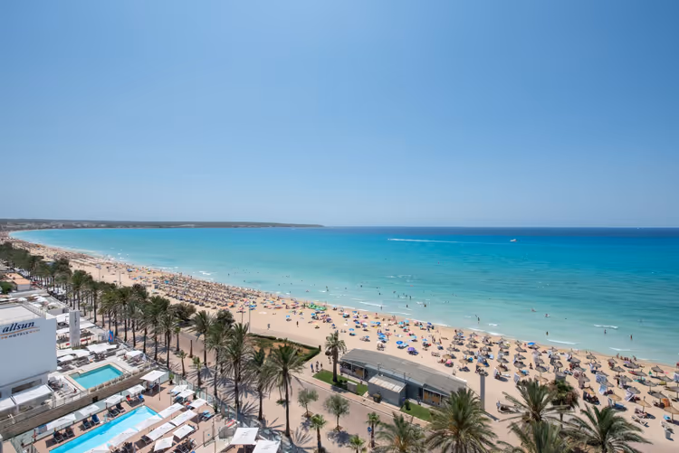 Strand met turquoise water, palmbomen en hotels langs de kustlijn