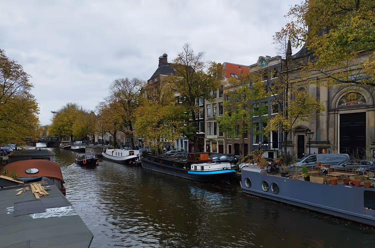 Amsterdamin kanava, jossa on asuntoveneitä ja historiallisia rakennuksia syksyllä