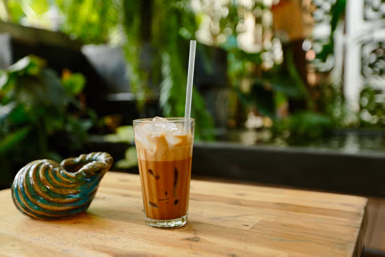 Glass med iskaffe og sugerør på et trebord