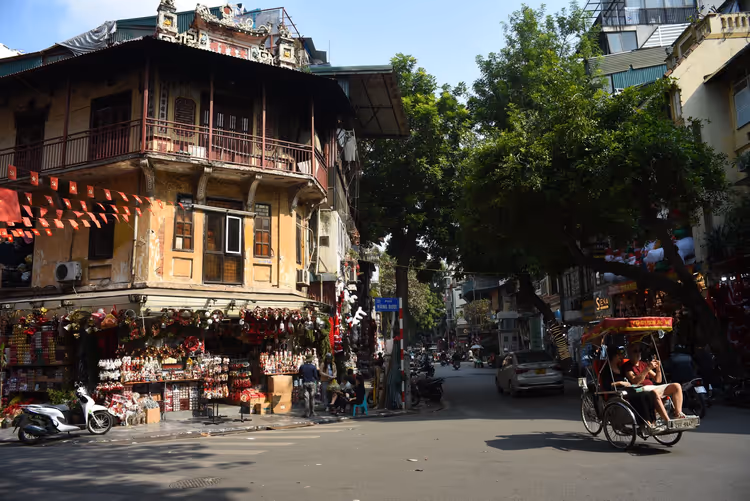 Straße in Hanoi mit einem traditionellen Haus und einer Rikscha