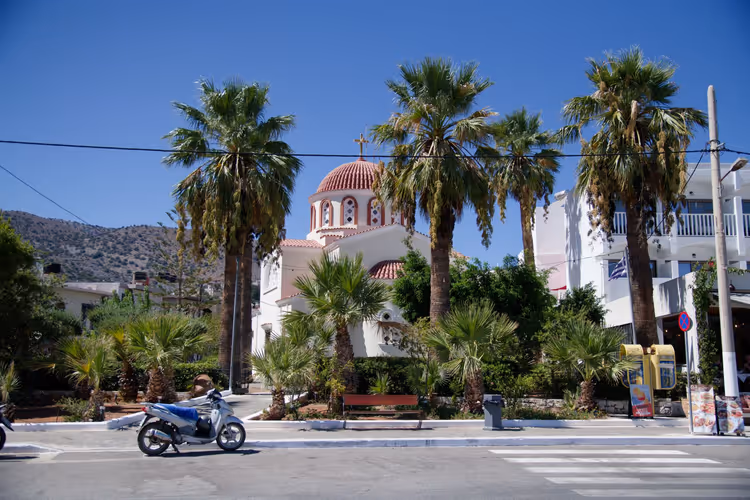 Kirche mit roter Kuppel und Palmen auf Kreta