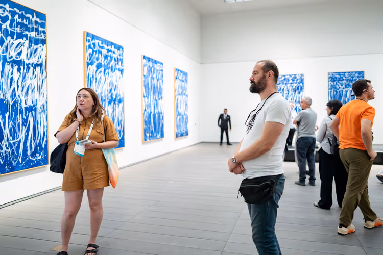 Bezoekers in een hal met blauwe abstracte schilderijen