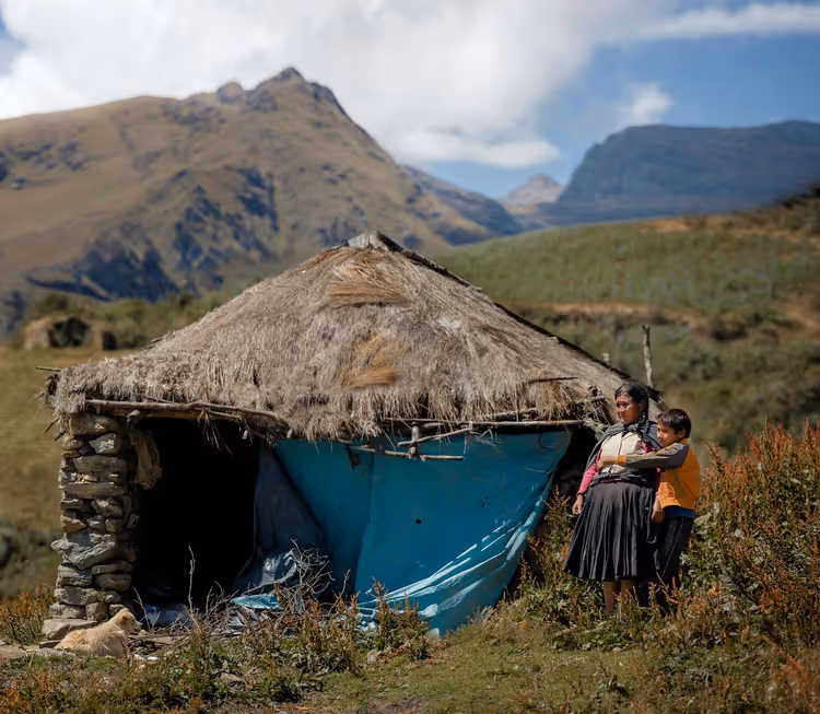 Kvinne og barn ved en hytte i fjellene i Peru