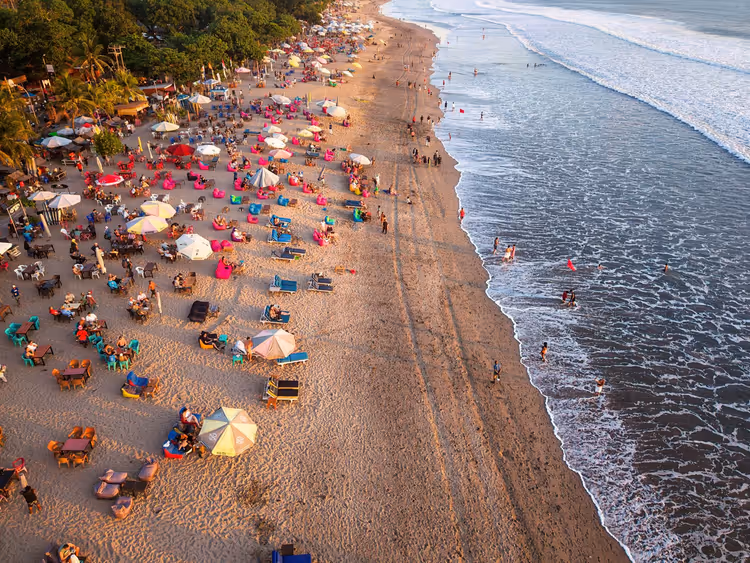 Belebter Canggu-Strand mit Sonnenschirmen bei Sonnenuntergang