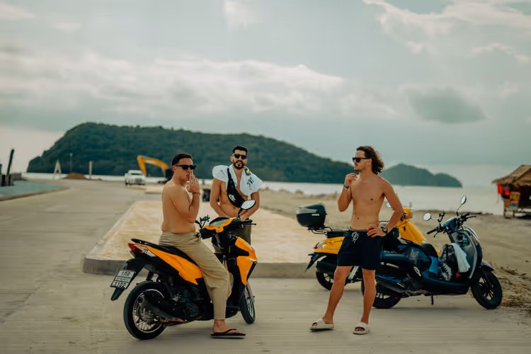 Trois gars avec des scooters loués au bord de la mer