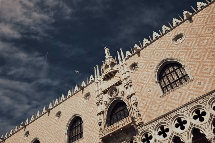 Den gotiske fasaden til Dogepalasset i Venezia mot en mørk himmel