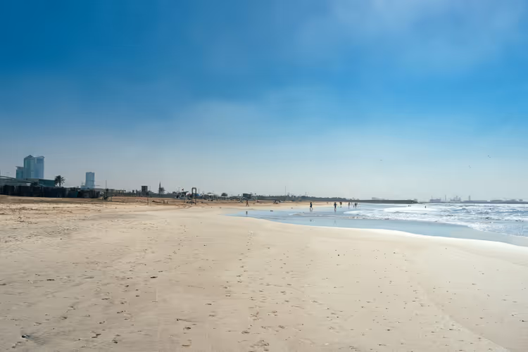 Strand i Sharjah med sjø og mennesker i det fjerne