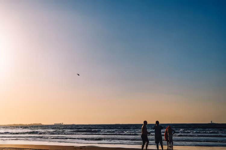 Silhuetter av mennesker på stranden i Sharjah ved solnedgang