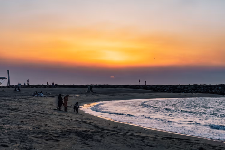 Solnedgang på Sharjah Beach med silhuetter av mennesker