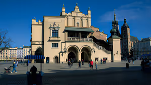 Mercato dei Tessuti nella piazza del Mercato di Cracovia, con portici, passanti e le torri di Santa Maria sotto un cielo blu intenso