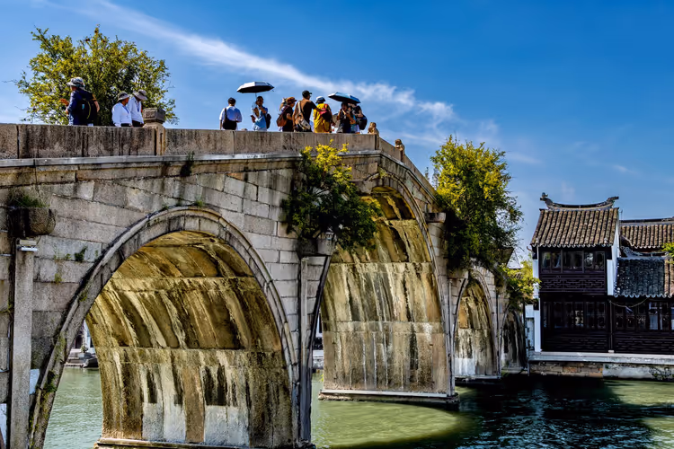 Touristen auf einer alten Steinbogenbrücke über einen Kanal