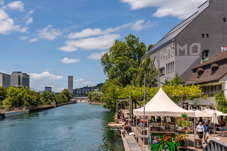Folk som slapper av ved elven i Zürich på en solrik dag