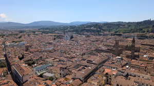 Terrakottadächer von Florenz von oben, mit Kirchtürmen und grünen Hügeln am Horizont