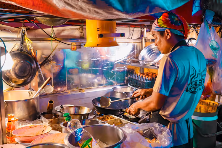 Straßenverkäufer, der auf dem Nachtmarkt Essen zubereitet