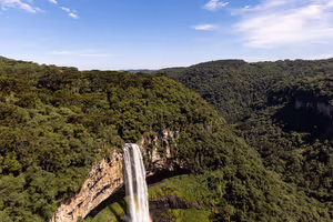 Hoher Wasserfall, der von einer Felswand stürzt, umgeben von dicht bewaldeten grünen Hügeln in Brasilien