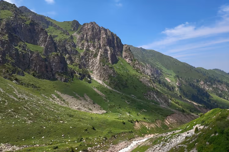 Klipperike fjellrygger i Tian Shan og grønne skråninger