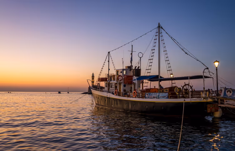 Sonnenuntergang über dem Hafen mit einem am Pier festgemachten Schiff