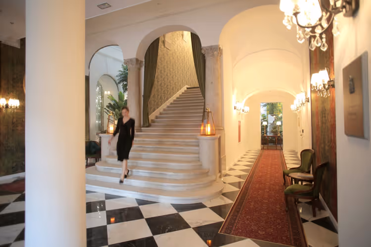 Lobby de hotel luxuoso com uma escadaria imponente e candelabros