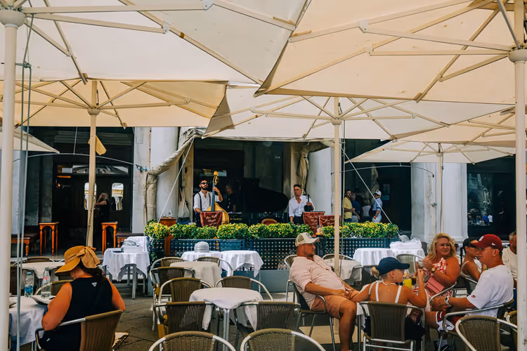 Gäste und Musiker unter Sonnenschirmen in einem Sommercafé