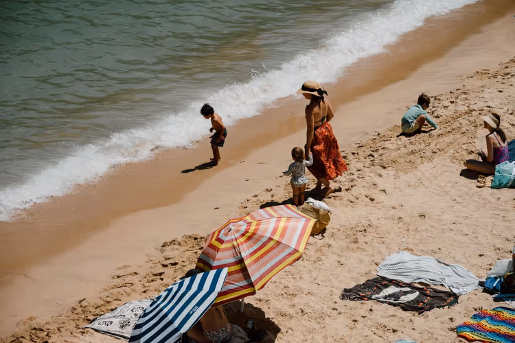 Familie med barn som slapper av på en sandstrand i Spania