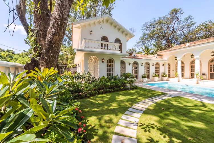 Weiße Villa mit Pool in einem tropischen Garten