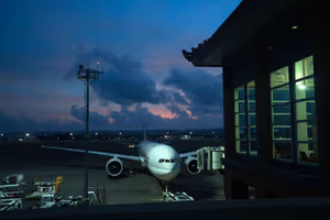 Großraumflugzeug am Gate eines Terminals in der Dämmerung unter dunklen, rosa getönten Wolken