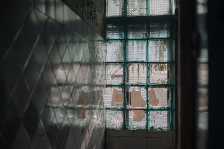 Flislagt vegg og glassblokker i et forlatt rom