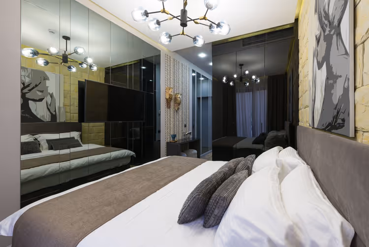 Modern bir apart otel odası, yatak ve aynalarla