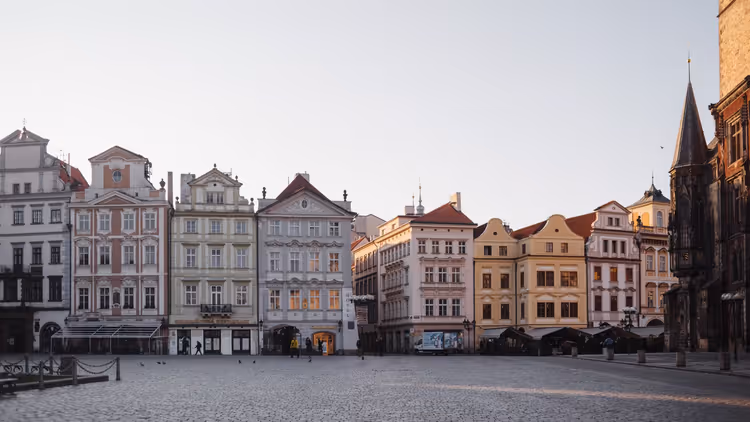 Pastellfarbene Barockfassaden am fast leeren, gepflasterten Altstädter Ring in Prag im weichen Licht des frühen Morgens