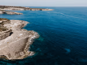 Luftaufnahme heller, flacher Kalksteinlandzungen, die an der Küste Maltas ins tiefblaue Meer ragen