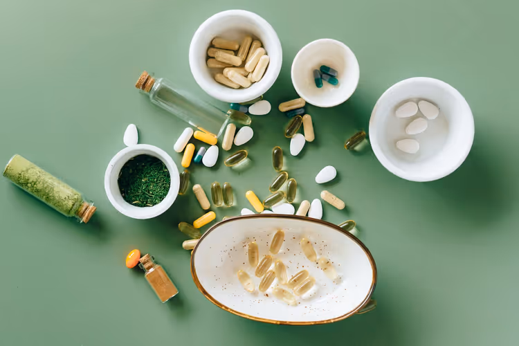 Vitaminen en supplementen in keramische schaaltjes op een groene achtergrond