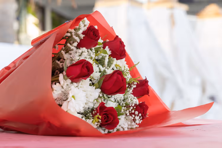 Bukett med røde roser og hvite blomster i rødt papir