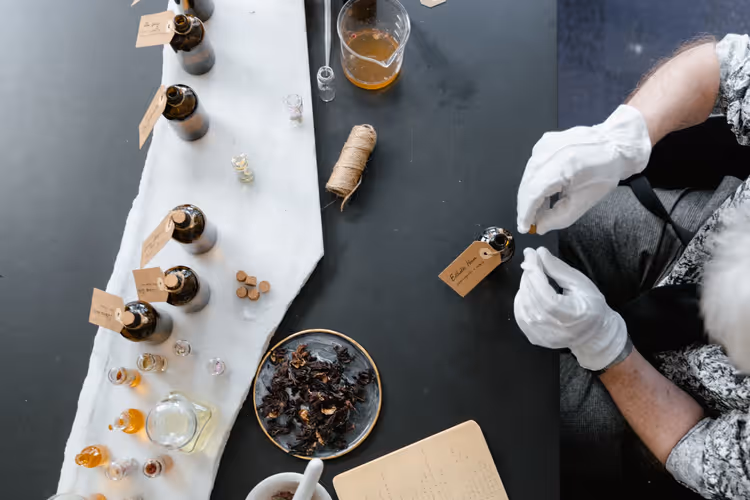 Parfymemaker i arbeid med flasker og ingredienser